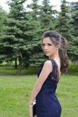 Beautiful formally dressed young woman standing outside in park