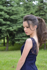 Naklejka premium Beautiful formally dressed young woman standing outside in park