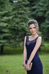 Beautiful formally dressed young woman smiling outside in park