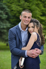 Young formally dressed couple hugging outside