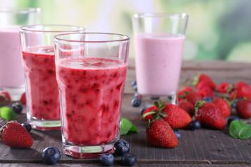 Glasses of berry smoothie on wooden table on blurred background