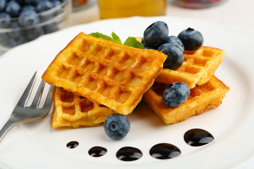 Sweet homemade waffles with forest berries and chocolate sauce on table background