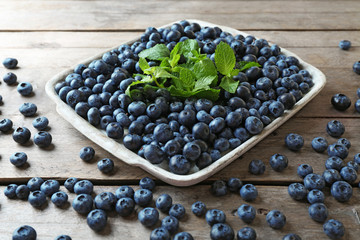 Tasty ripe blueberries with mint on wooden table close up