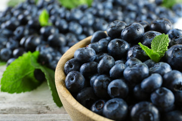 Tasty ripe blueberries with mint in bowl on table close up