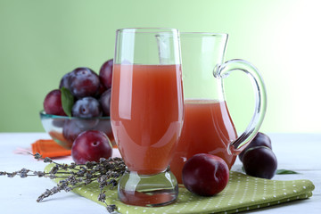 Delicious plum juice with fruits on green background