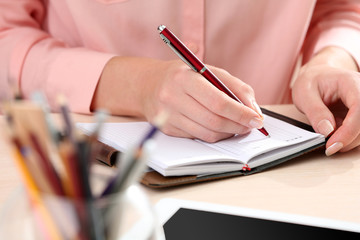 Woman write on notebook on workplace close up