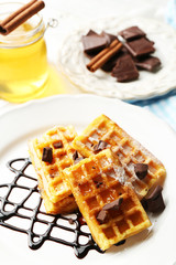 Sweet homemade waffles with chocolate sauce on plate, on light background