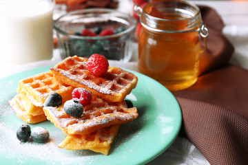 Sweet homemade waffles with forest berries on plate, on light background