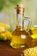 Fresh corn with bottle of oil on bright background