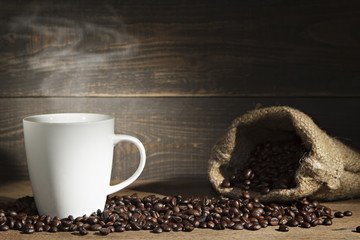 Coffee cup and coffee beans on wooden background.