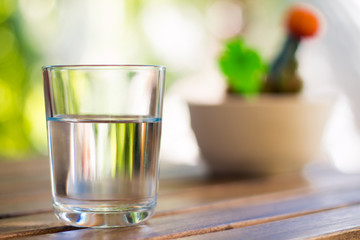 glass of water on wooden table bokeh background - vintage style picture