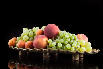 White grapes on a black background with peaches and apricots