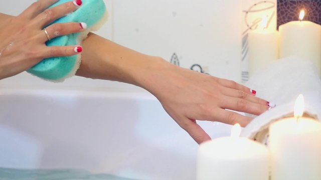 Woman wash her hands in a bath with foam.