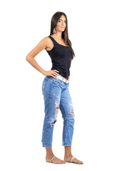 Obraz premium Side view of young confident female posing at camera with hand on her hip