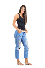 Obraz premium Young happy tanned woman with hands in pocket smiling at camera