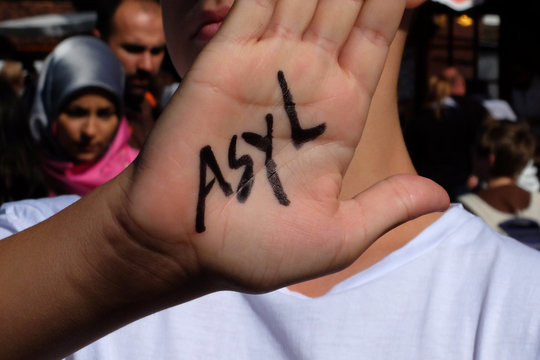 Ein Kind h&auml;lt die Hand hoch, auf der "Asyl" geschrieben steht