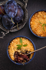 crumble with plums and cinnamon on a black background