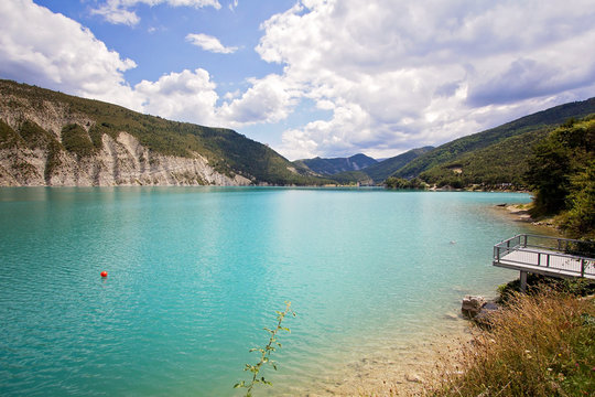 Beautiful green water of Lake Castillon reflects the sky and woo