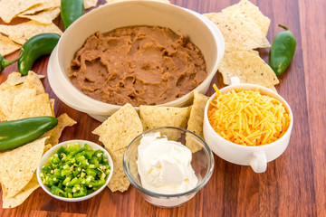 preparation of bean dip with jalapenos, sour cream and cheddar c