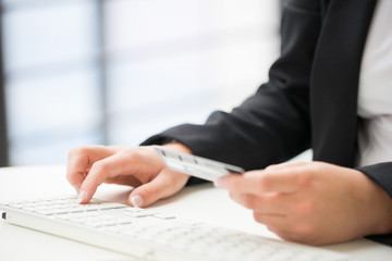 Fototapeta premium Hands of an office woman typing keyboard with credit card