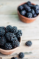 Fresh sweet blackberry in clay pots on a wooden table, closeup