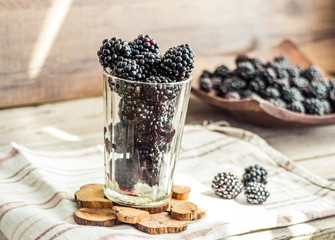 Fototapeta na wymiar fresh organic blackberries in a glass on a gray wooden table, ru