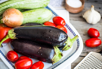 fresh vegetables for ratatouille on gray wooden table, rustic