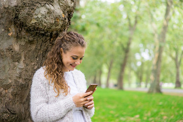  Young woman using mobile phone & message in summer park