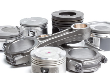 a set of pistons and rods for automobile engine on a white background