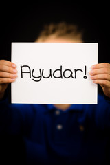 Child holding sign with Spanish word Ayudar - Help