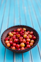 Earthenware bowl of juicy cherries on rustic wooden turquoise table