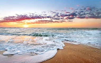Fotobehang Kleurrijke oceaanstrandzonsopgang met diepblauwe hemel en zonnestralen. © vrstudio