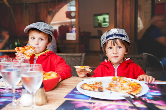 Sweet Adorable Children, Two Boys, Eating Pizza At A Restaurant