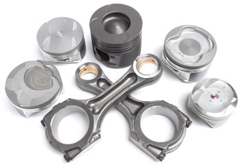 a set of pistons and rods for automobile engine on a white background