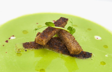 pea soup with croutons on a white dish at restaurant