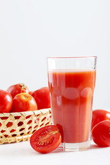 Fresh red tomatoes and tomato juice in glass on wooden table