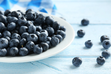 Blueberries in plate on a blue wooden background