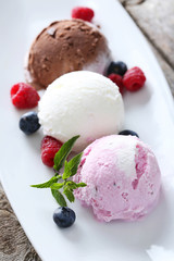 Ice cream on plate with berries on grey wooden background