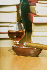 Zapalone cygaro z drinkiem na tle książek © GieZetStudio