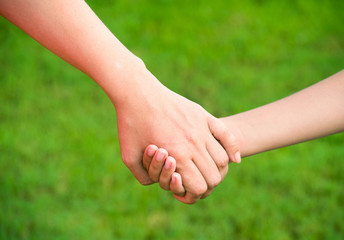 Mother holding a hand of his son in summer day outdoors