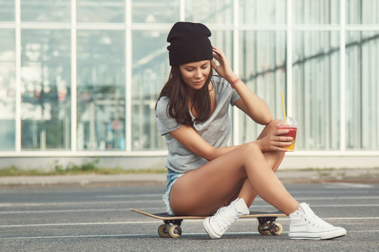 Beautiful woman sitting on skateboard