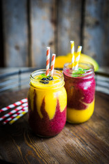 Colorful two layer smoothies with mango and berries on rustic wo