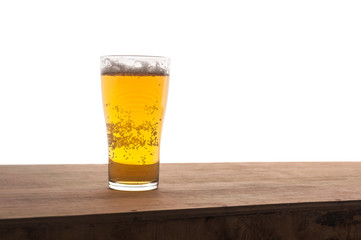 Glass of beer on wooden bar isolated