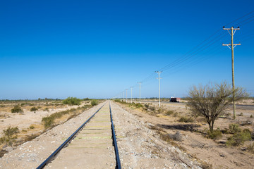 Fototapeta na wymiar Straight train rails in the north of Argentina with blue sky