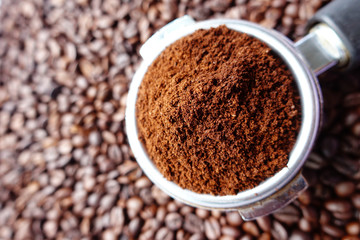 Freshly ground coffee beans in a metal filter on coffee beans background 