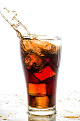 Ice cube droped in cola glass and cola splashing