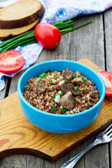 Buckwheat with meat and tomatoes on a wooden background
