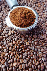 Freshly ground coffee beans in a metal filter on coffee beans background 
