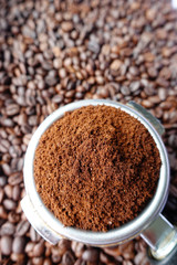 Freshly ground coffee beans in a metal filter on coffee beans background 