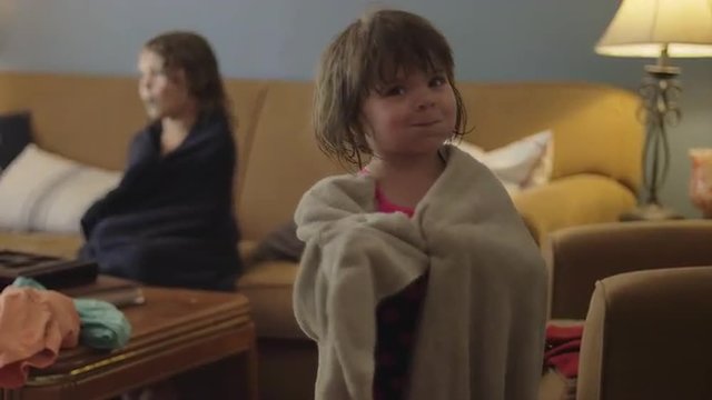A cute little girl in wrapped in a towel being silly
